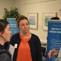Student, alumna and faculty talking to one another at the Academic Major Fair.